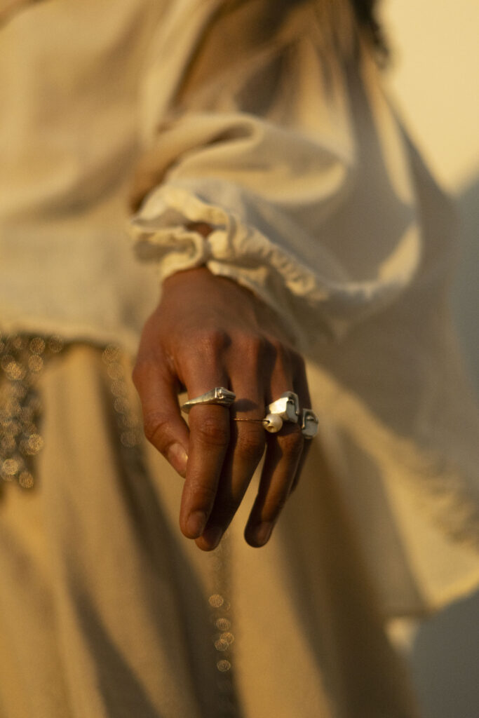 Mano con anillos de plata artesanal mexicana de Cara de Niño, diseño imperfecto y hecho a mano.